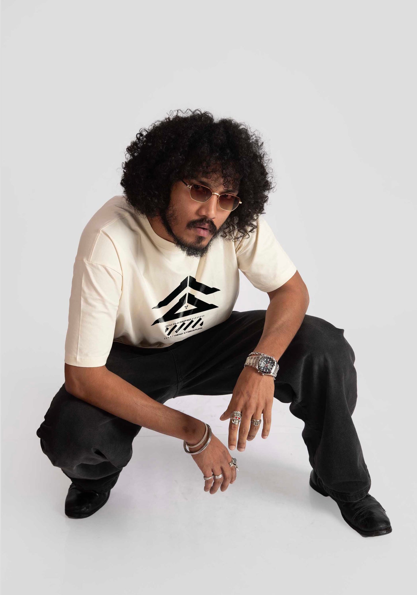 Man wearing Stylera cyberpunk oversized t-shirt in cream with black graphic design and black pants
