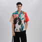 Model wearing Stylera men's printed resort shirt with colorful dog and tropical leaf watercolor print