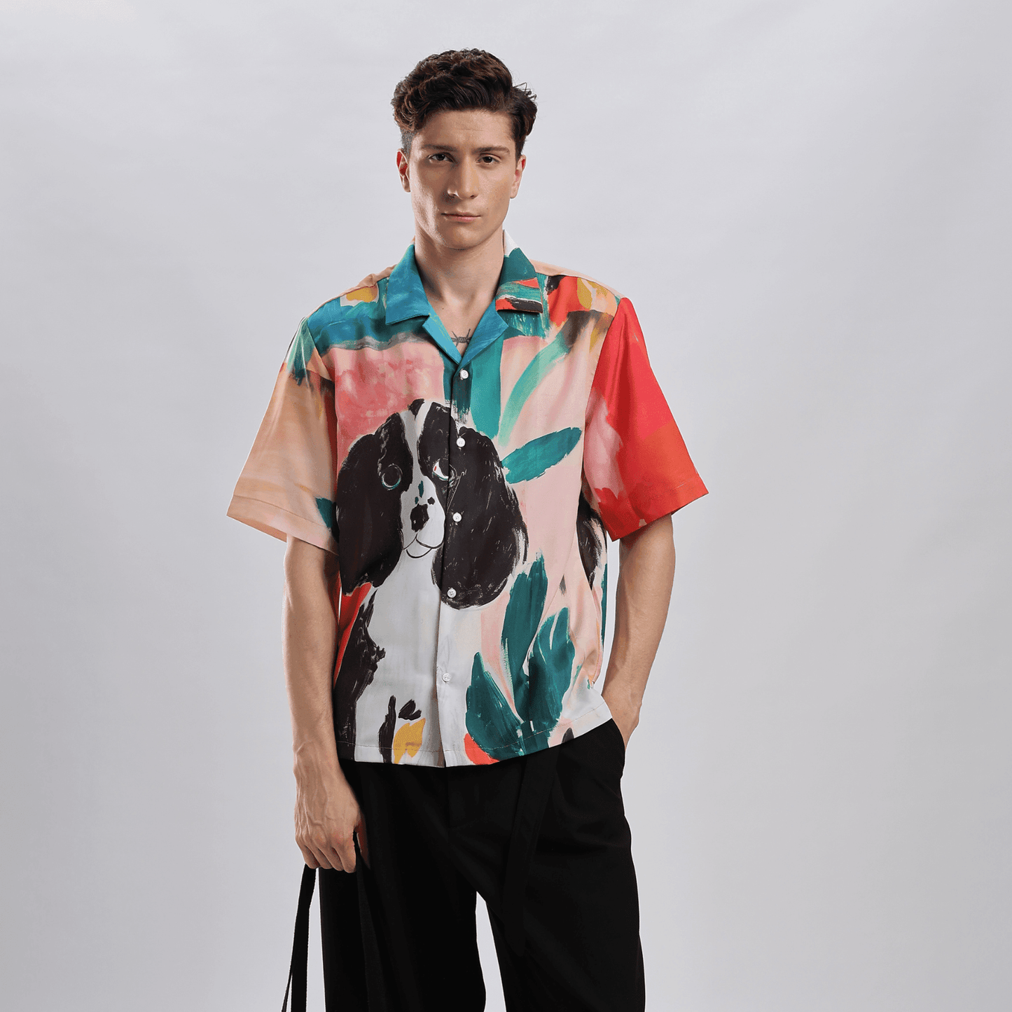 Model wearing Stylera men's printed resort shirt with colorful dog and tropical leaf watercolor print