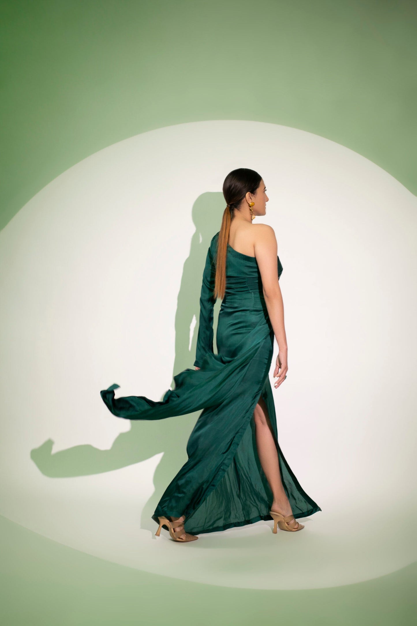 Elegant green Stylera designer single sleeve gown with a flowing skirt perfect for formal events. Buy designer single sleeve gown.