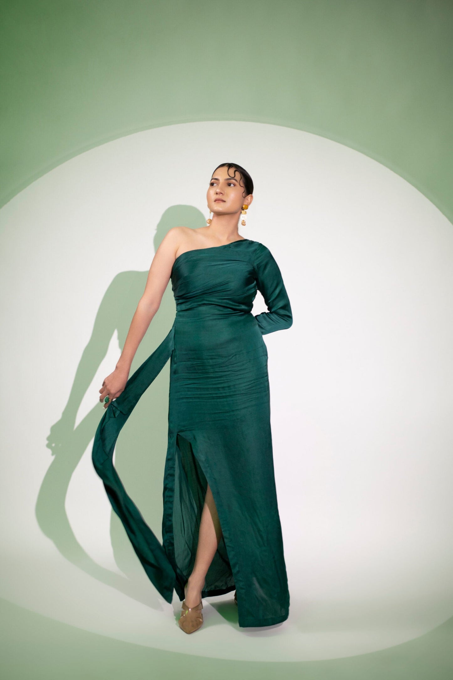 Elegant dark green designer single sleeve gown with a side slit, perfect for evening wear