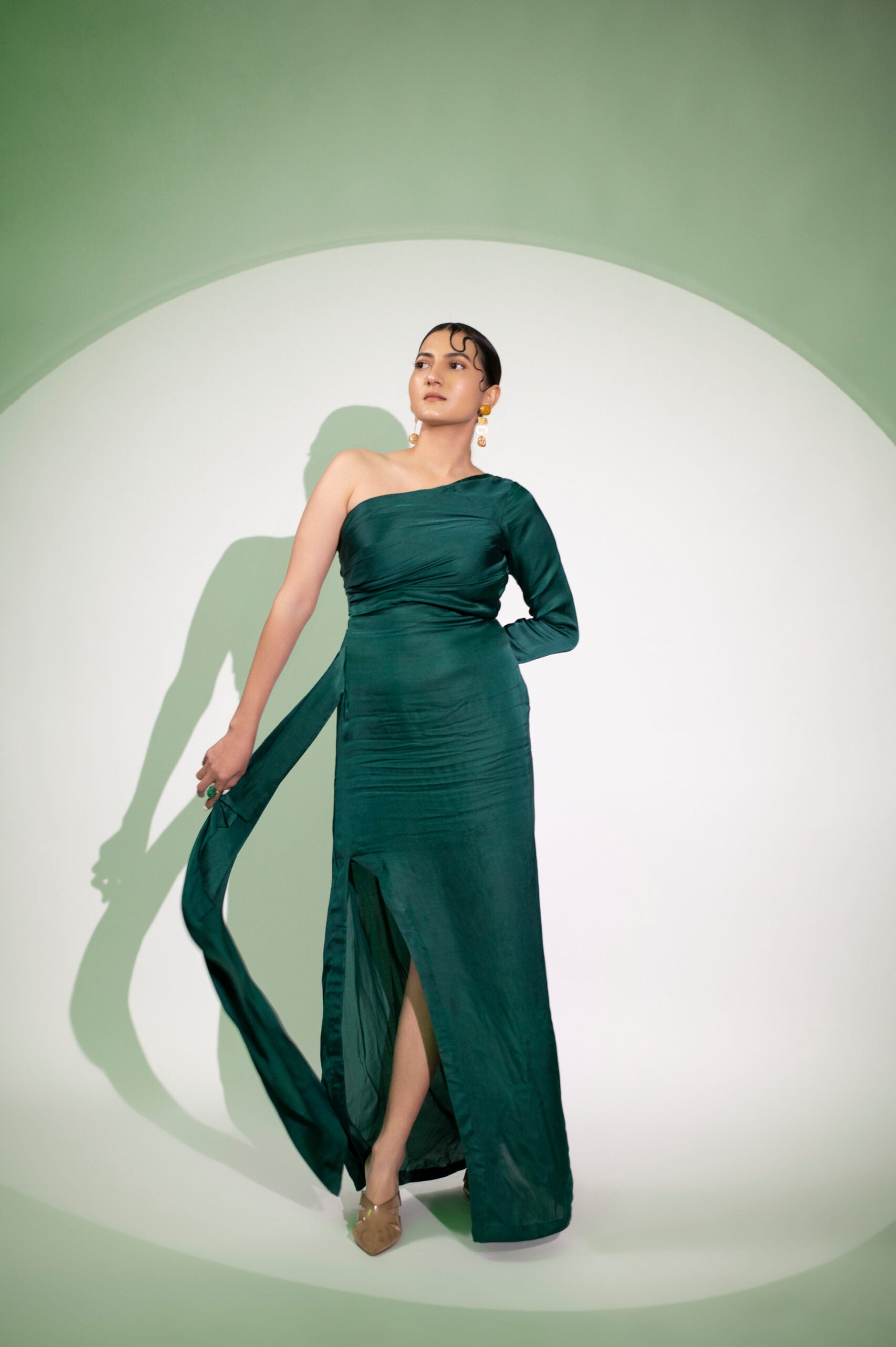 Elegant dark green designer single sleeve gown with a side slit, perfect for evening wear