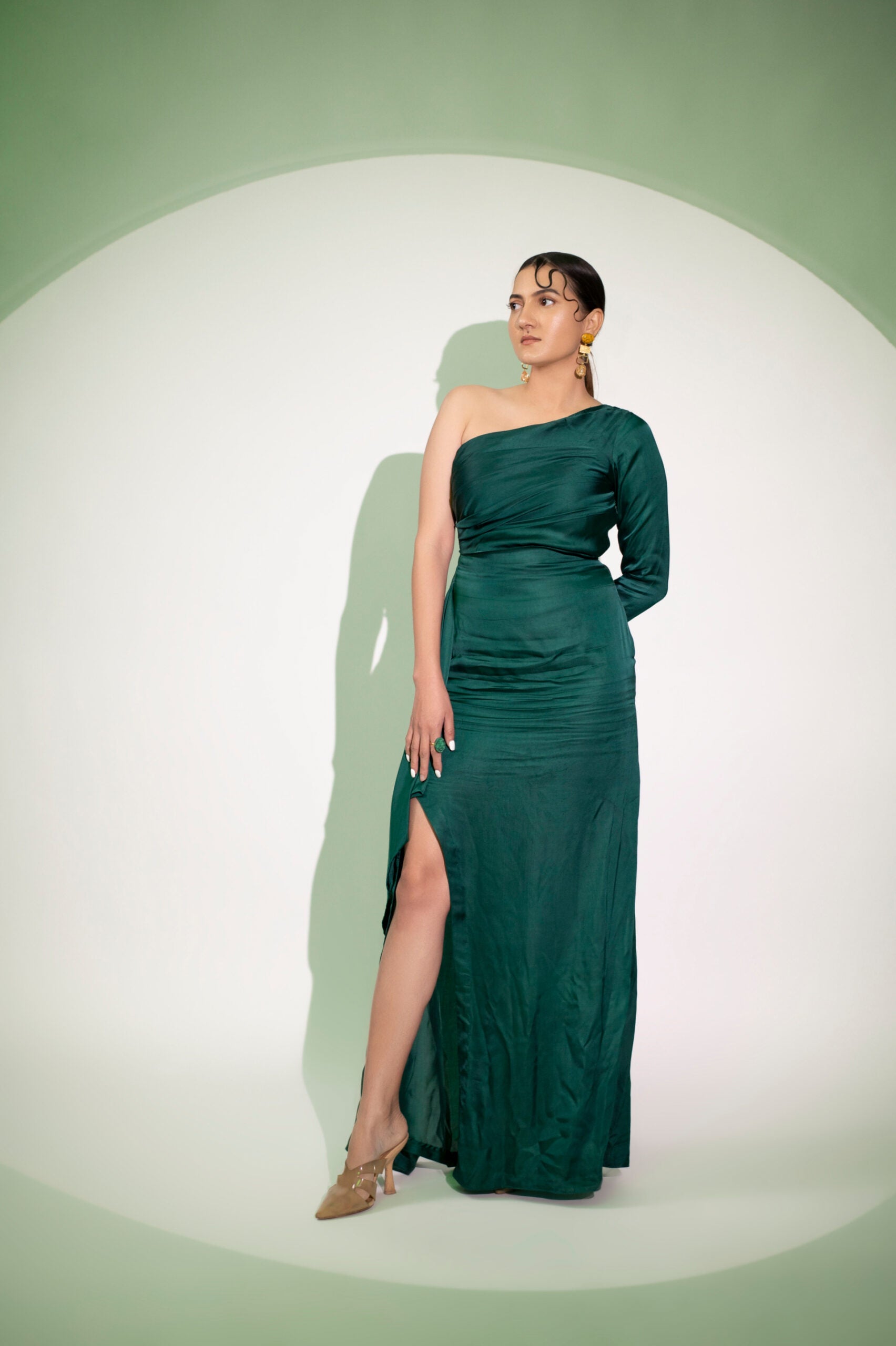Elegant designer single sleeve gown in green with thigh-high slit for a stylish evening look