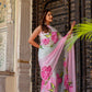 Elegant woman in a pink floral chiffon saree posing by a traditional door, perfect to buy trendy chiffon saree