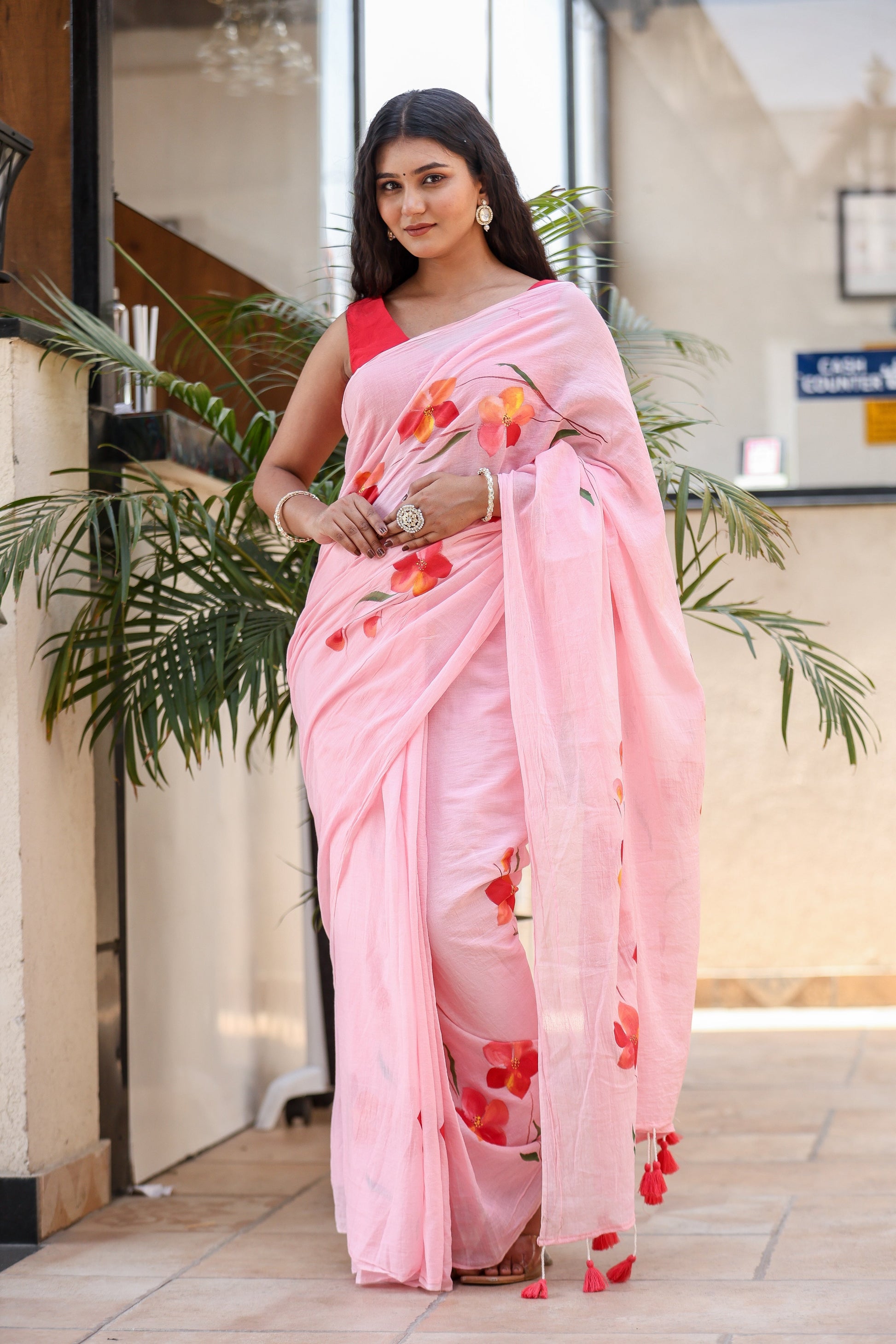 Model wearing a pink malmal saree with floral designs, perfect for casual wear. Buy trendy malmal saree.