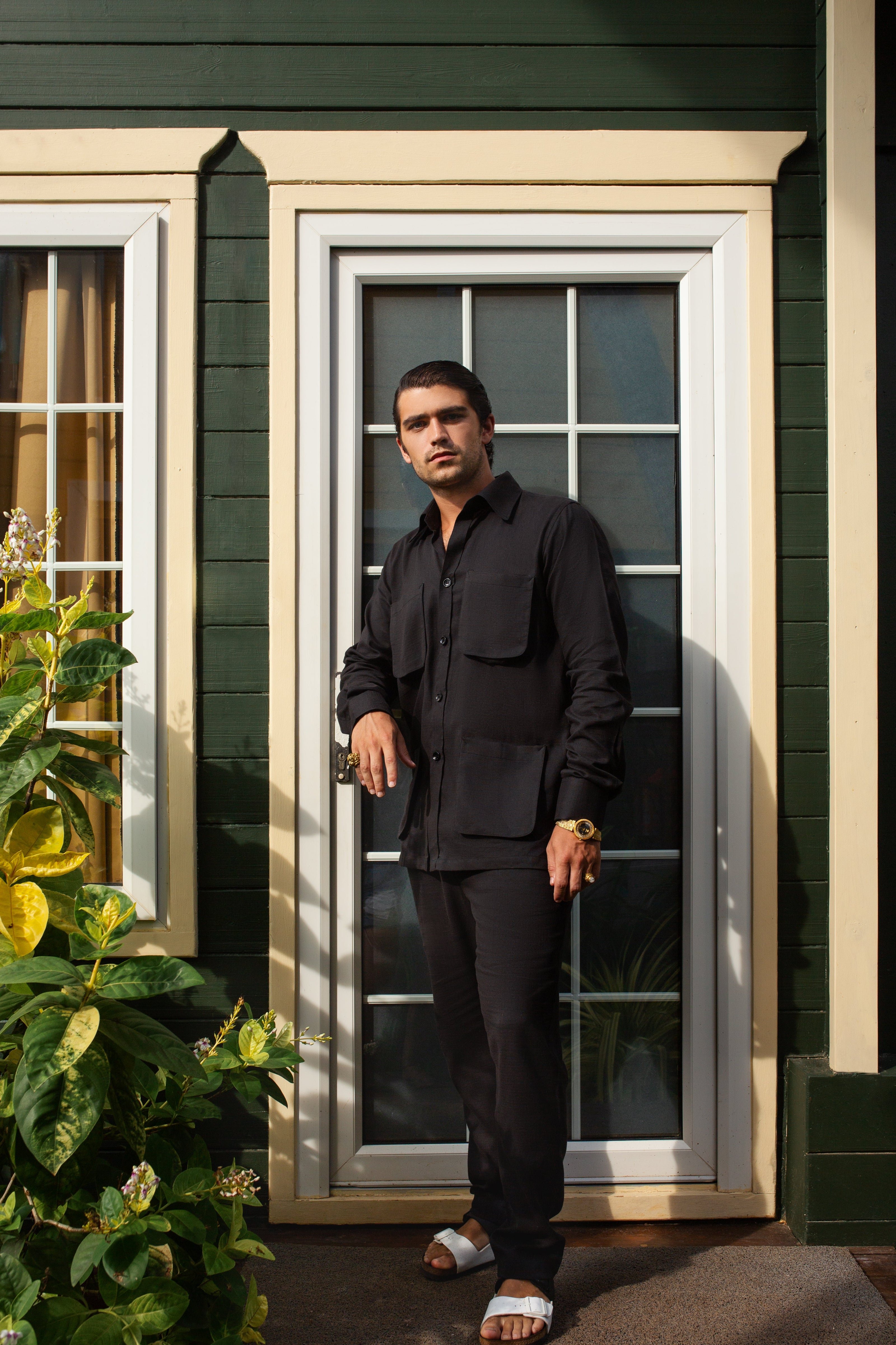 Man in casual black outfits for men standing by a door with stylish casual wear