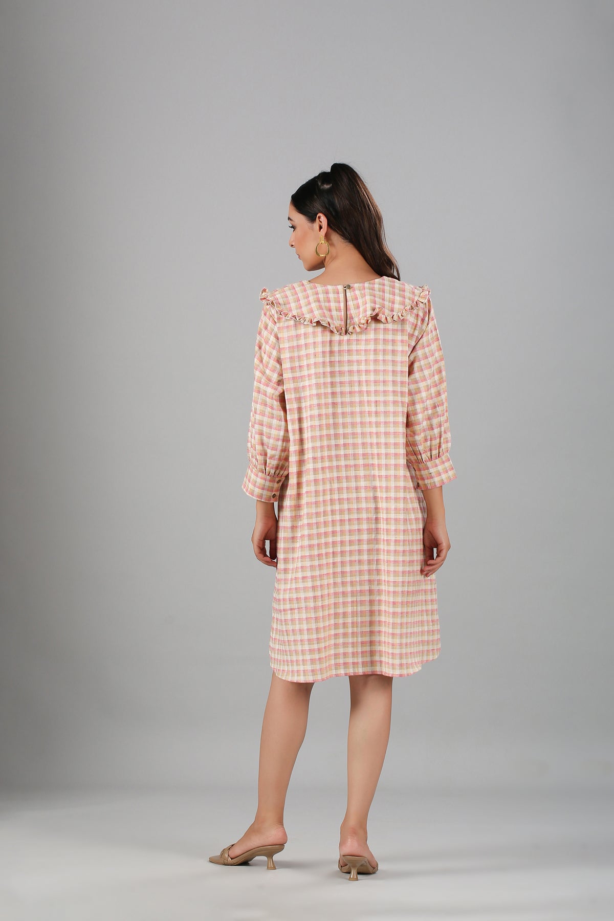Back view of a casual checkered dress for women in pink and white with ruffled neckline details