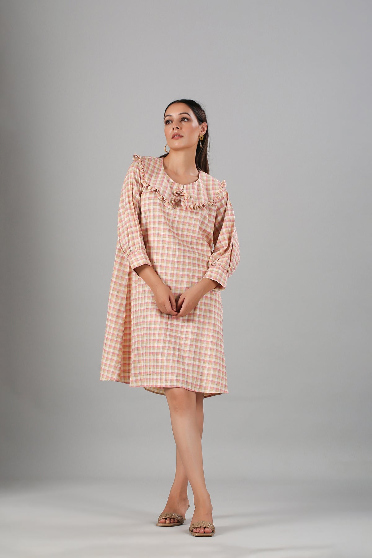 Stylish casual checkered dress for women with ruffled detail and long sleeves in peach tones