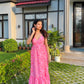 Woman in a pink casual floral maxi dress from Stylera standing on lawn by modern house