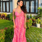 Woman in pink printed casual floral maxi dress with spaghetti straps and ruffled hem standing in garden