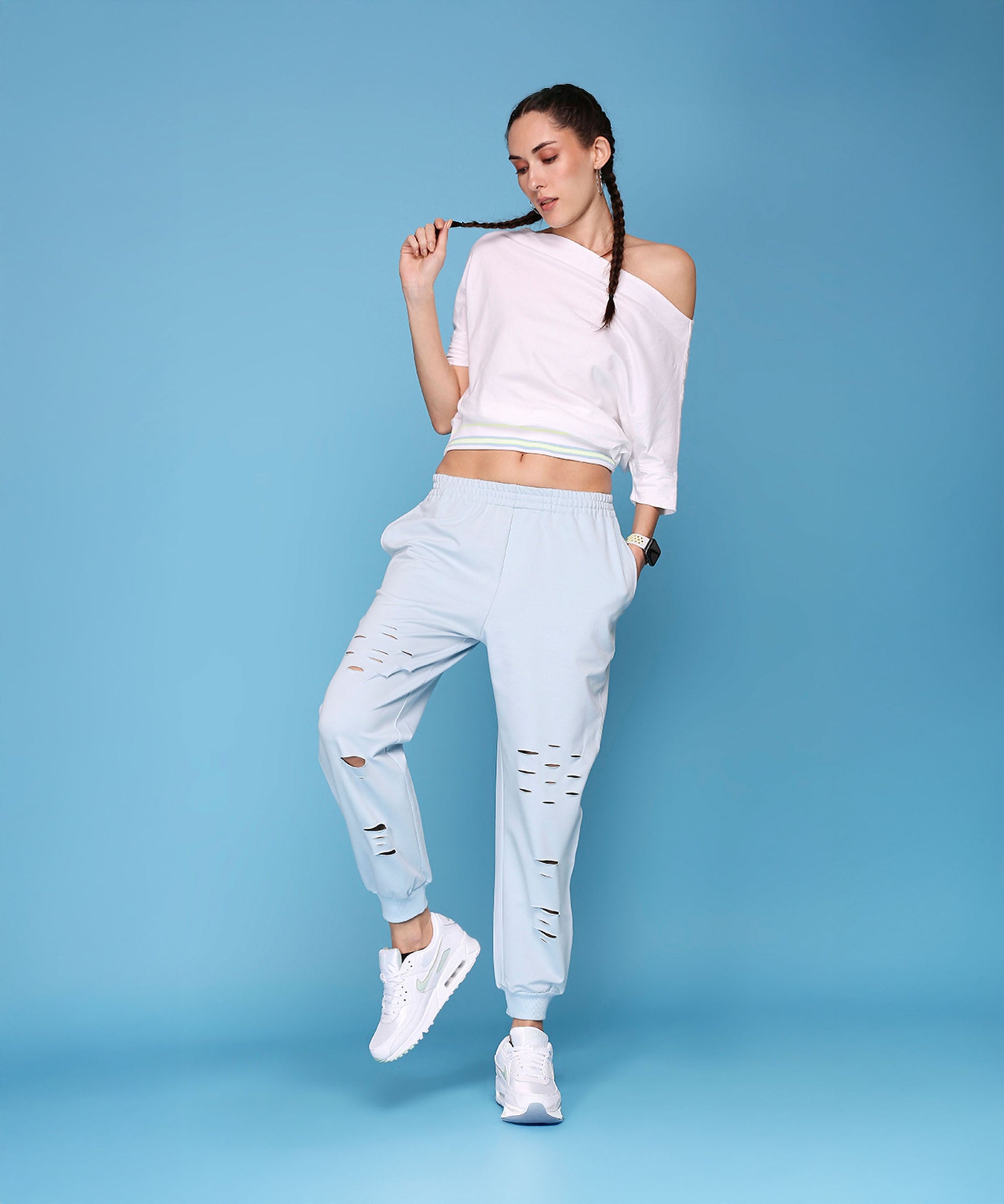 Model wearing a casual off shoulder lounge set in light blue with stylish ripped details