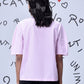 Back view of model wearing casual pink top for women by Stylera with short sleeves and boxy fit
