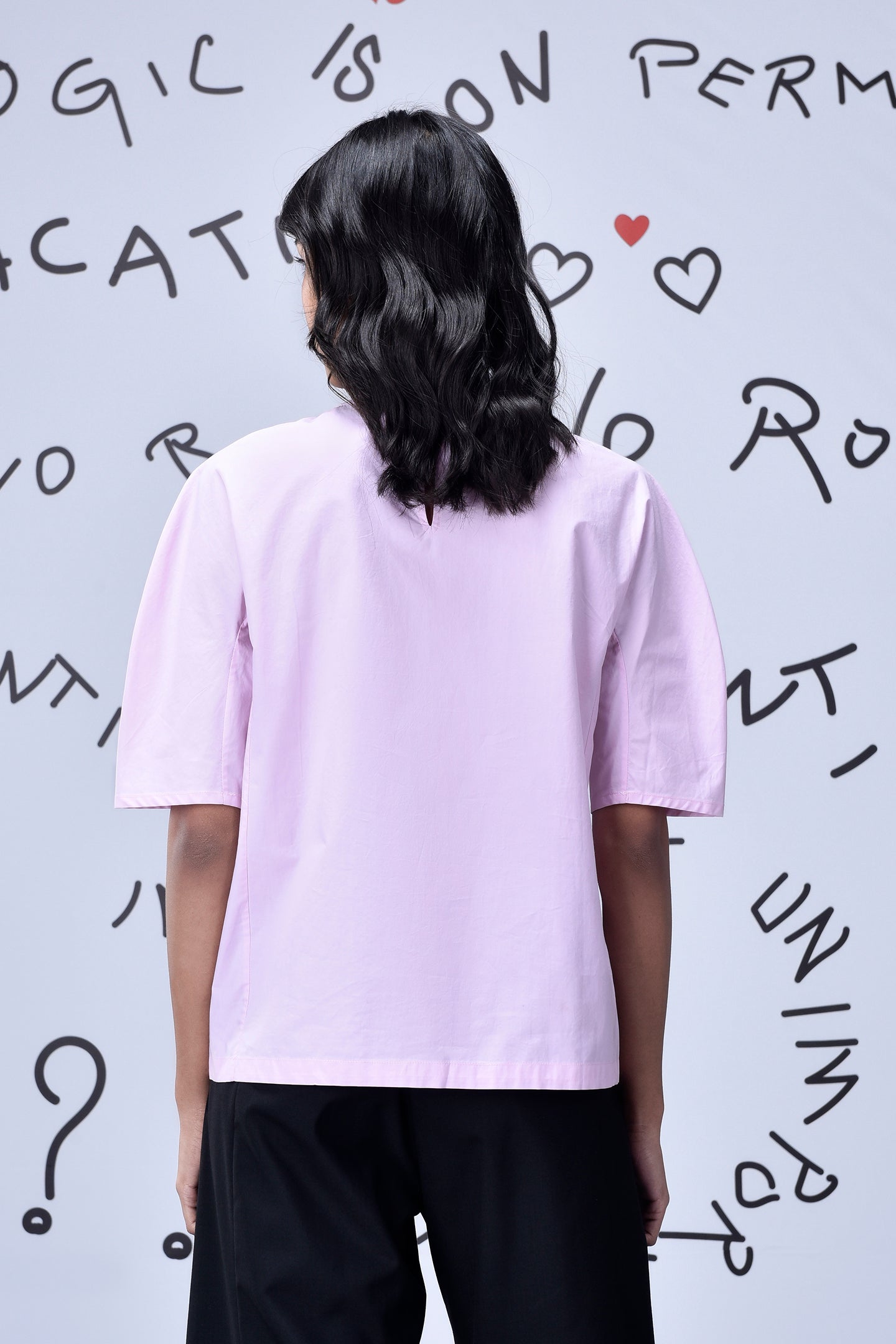 Back view of model wearing casual pink top for women by Stylera with short sleeves and boxy fit