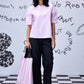 Stylera casual pink top for women worn with black trousers and striped tote on checkered floor