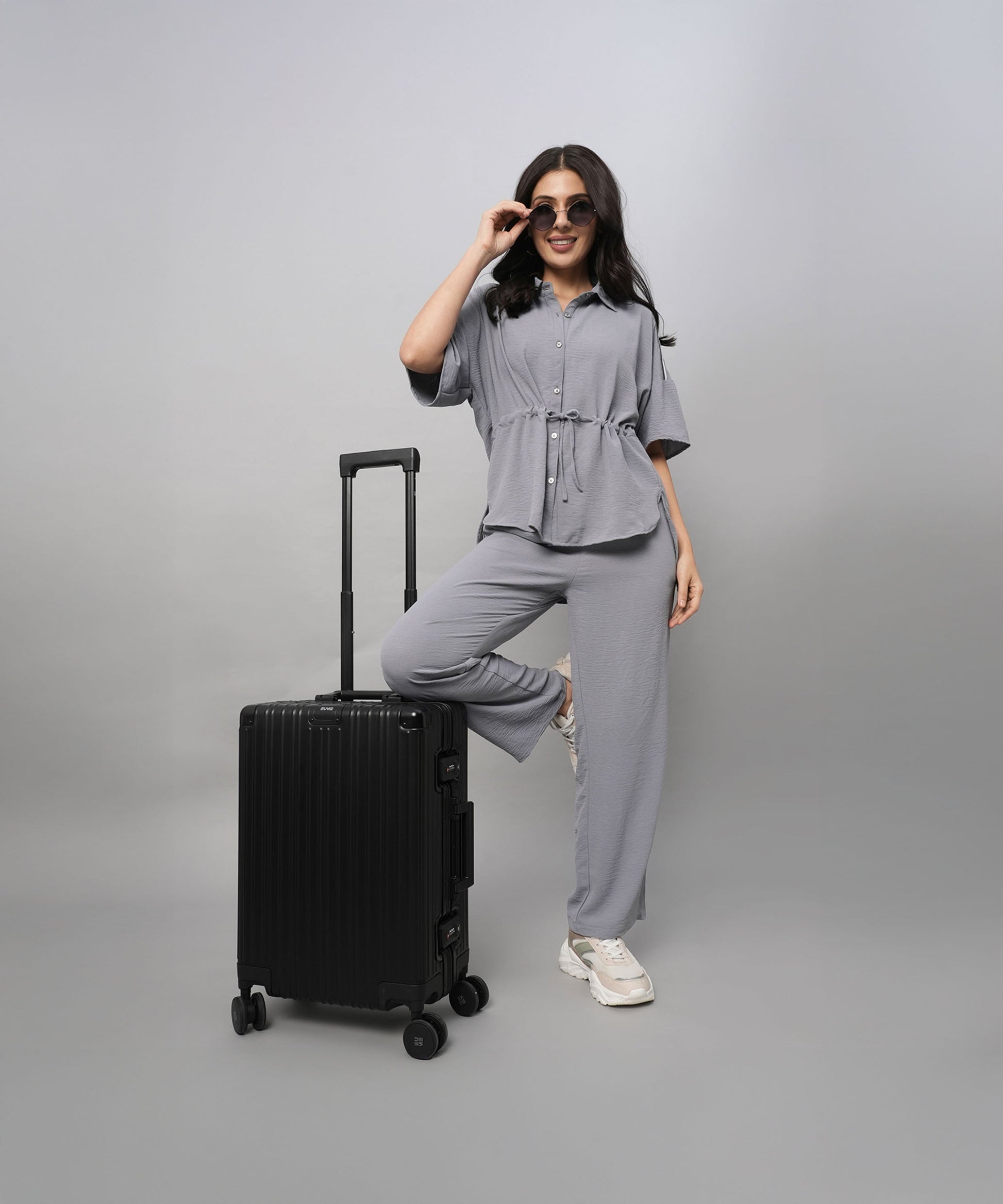 Stylish gray casual two piece outfit for women with a relaxed fit, paired with a black suitcase