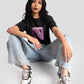 Woman wearing a charcoal black oversized crop top with graphic print paired with light blue jeans and sneakers
