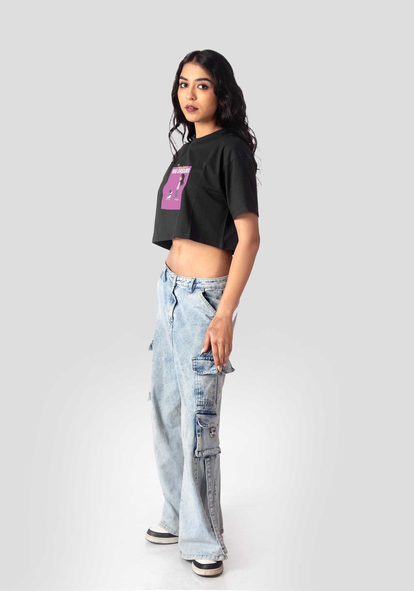 Woman wearing charcoal black oversized crop top paired with light blue cargo jeans and sneakers