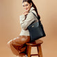Fashion model showcasing charcoal chic bucket bag sitting on a stool in stylish attire