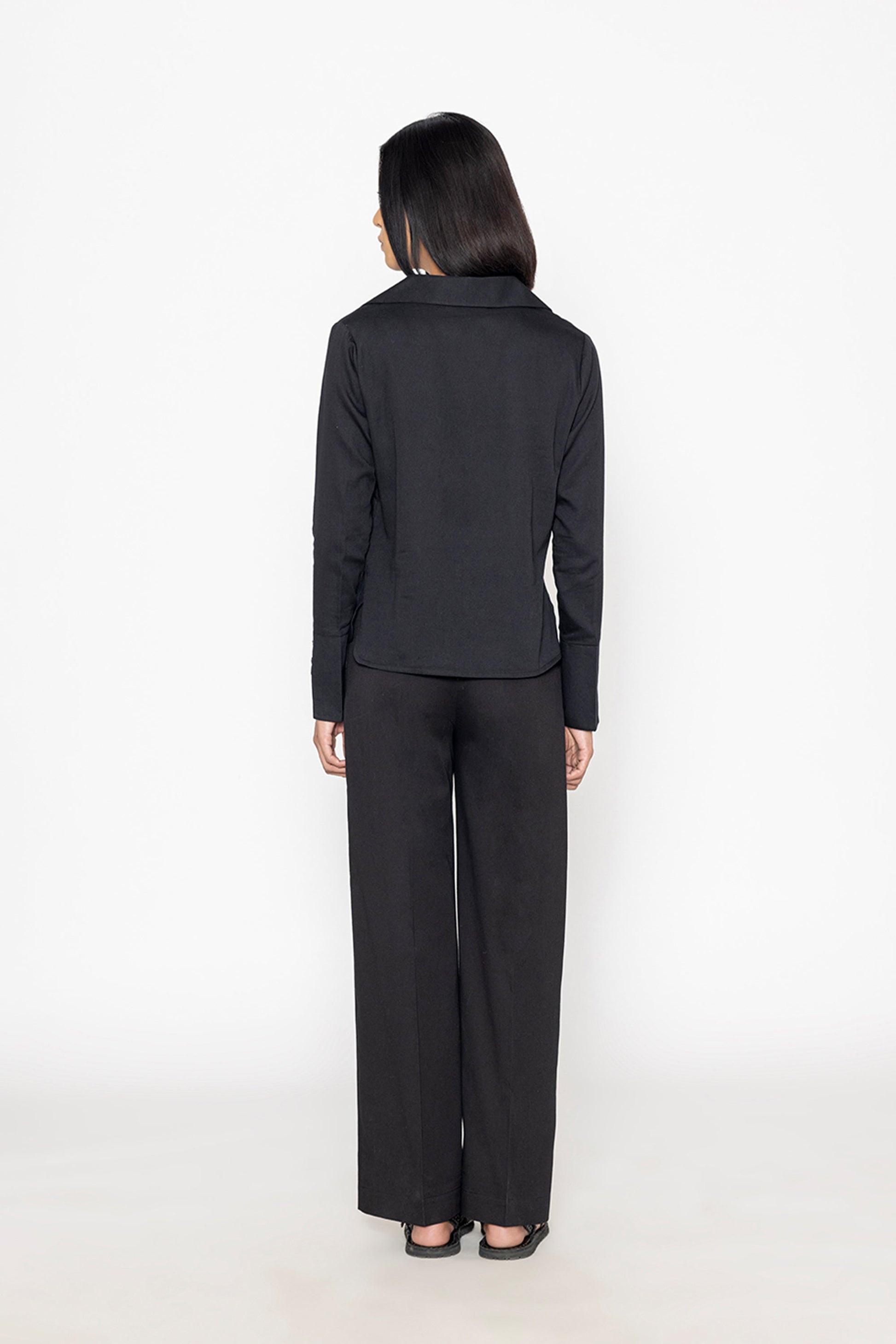 Back view of a chic black blouse for women by Stylera paired with matching black wide-leg pants