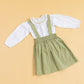 Children's pinafore dress with suspenders in light green paired with a white ruffled blouse