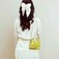 Citrus color shoulder bag styled on model with white bow hairstyle for chic outfits