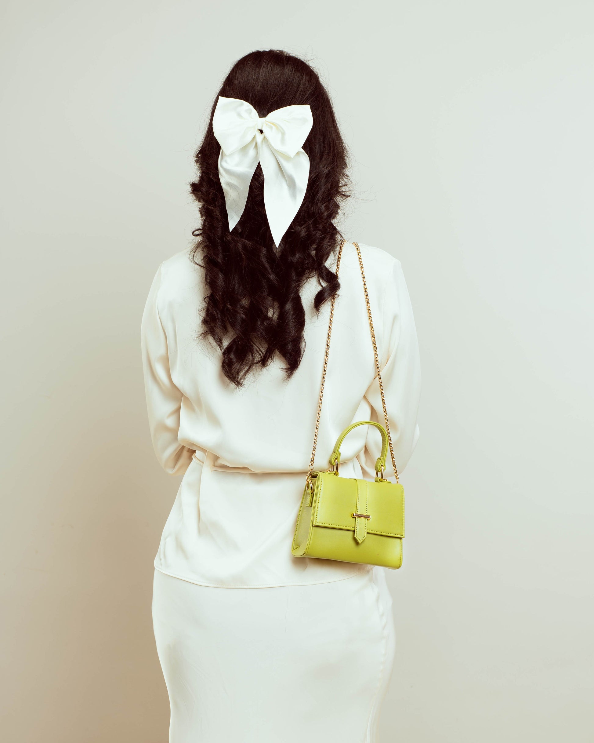 Citrus color shoulder bag styled on model with white bow hairstyle for chic outfits