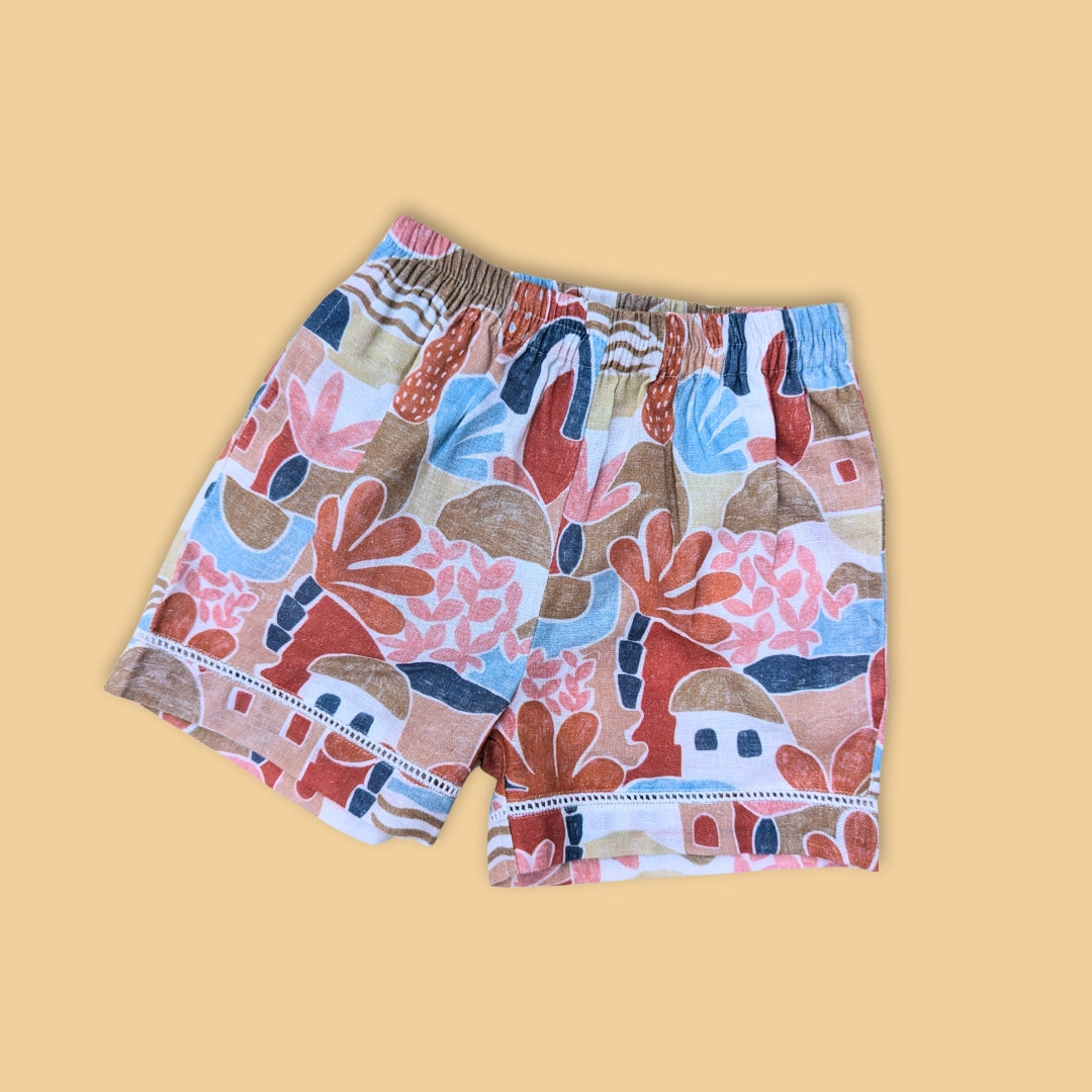 Colorful casual shorts with a vibrant abstract design featuring trees and houses
