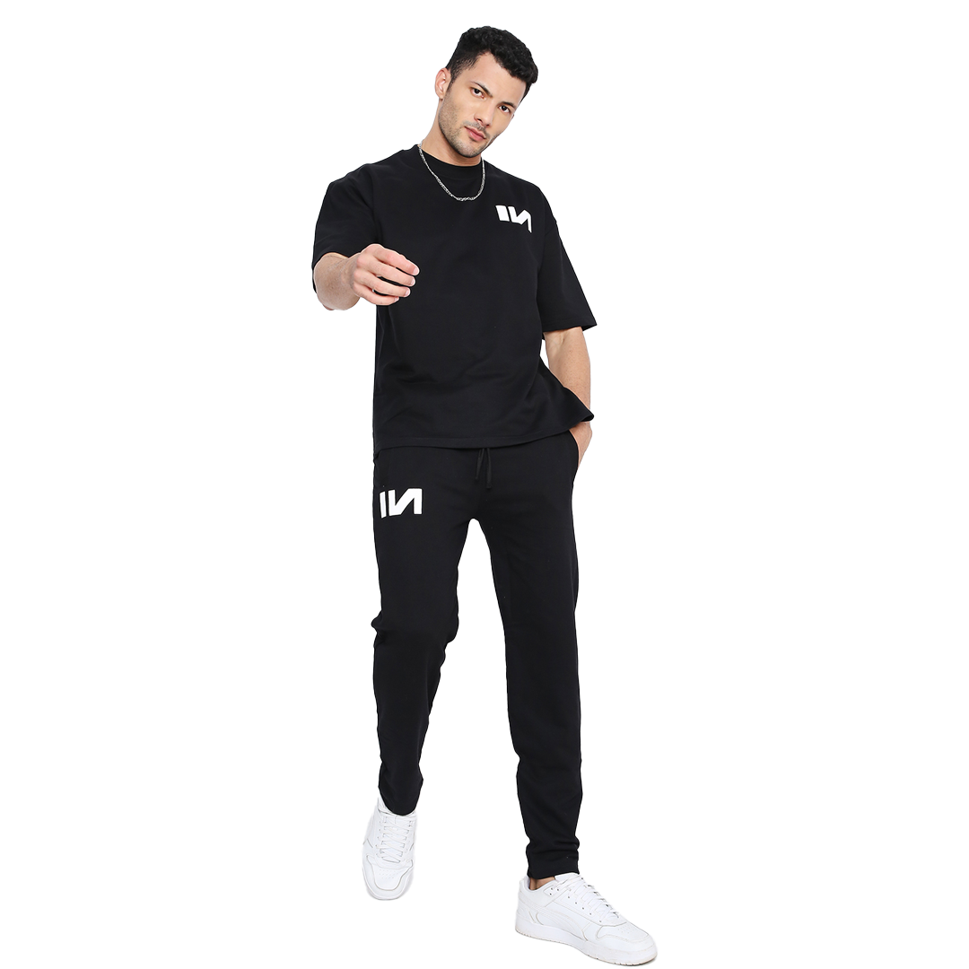 Stylera First black logo sweatpants on male model with white sneakers casual slim fit comfortable everyday sweatpants