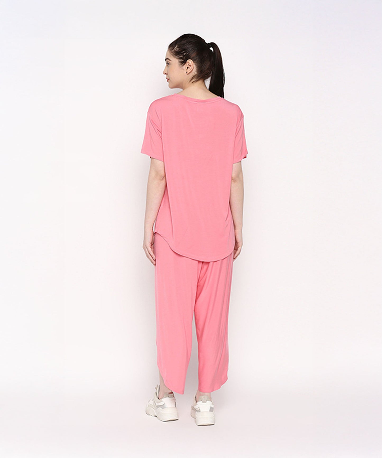Back view of a woman wearing a comfortable summer co-ord set in bright pink, featuring a loose t-shirt and flowy pants