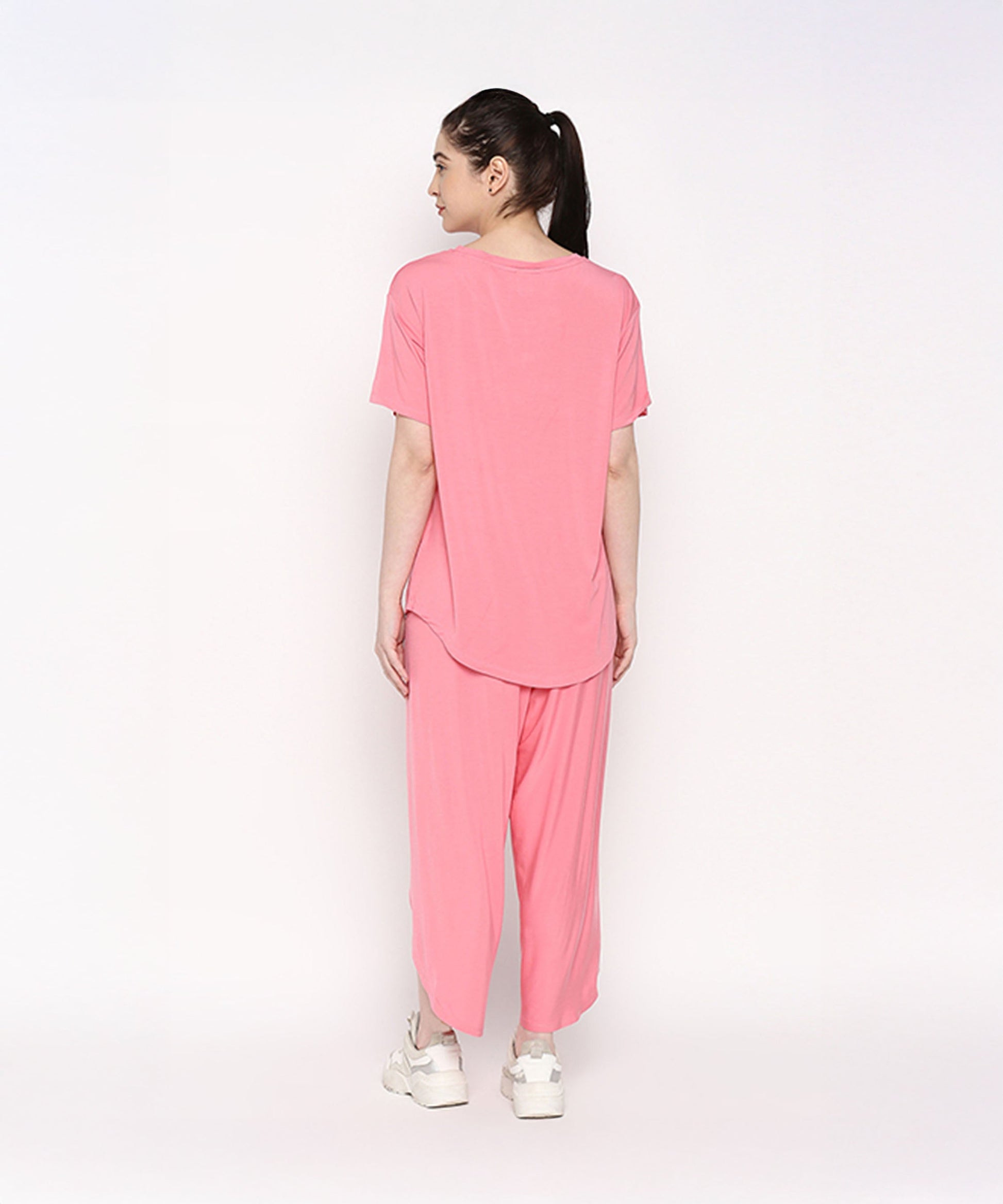 Back view of a woman wearing a comfortable summer co-ord set in bright pink, featuring a loose t-shirt and flowy pants