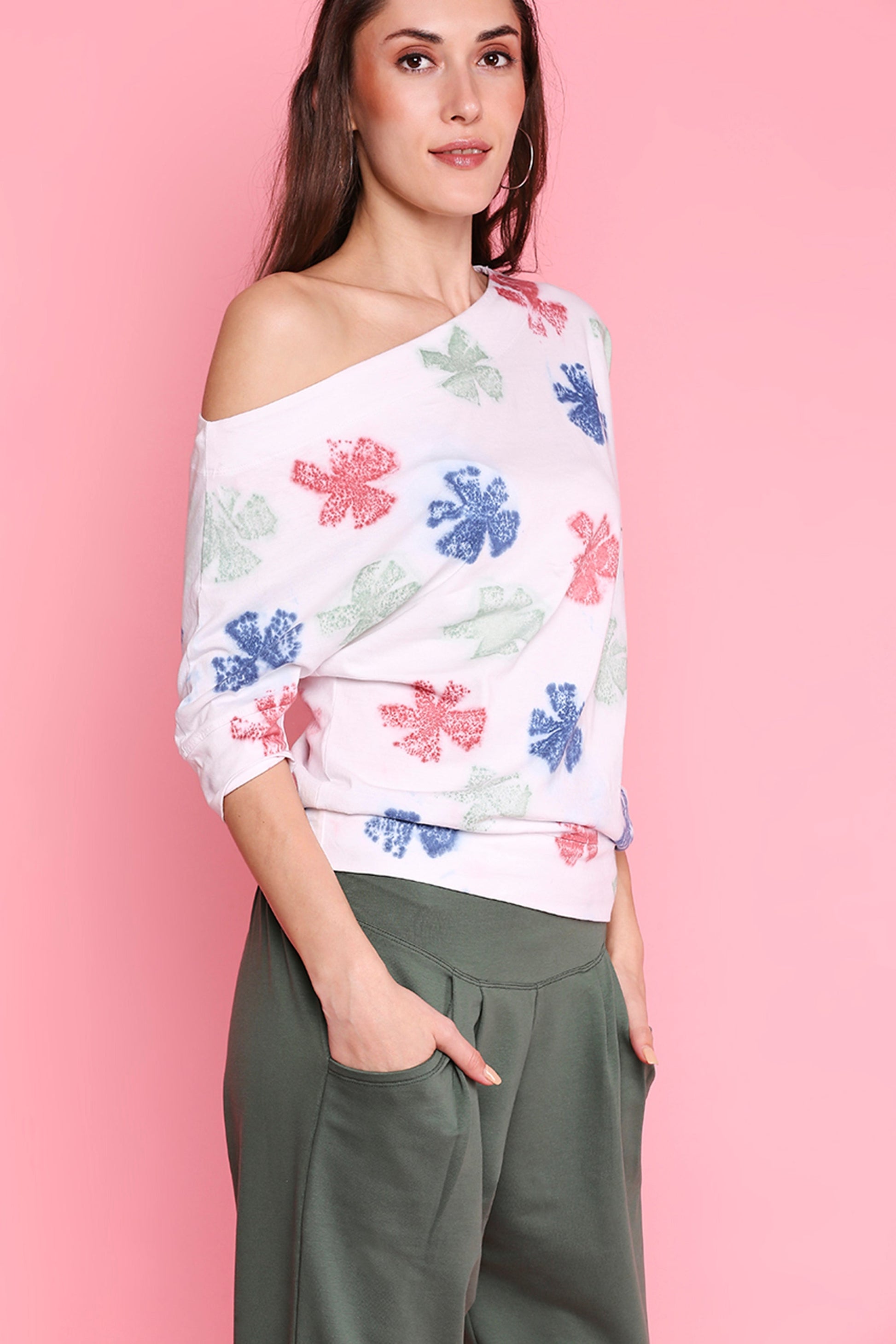 Woman wearing comfortable yoga pants with pockets and a colorful floral off-shoulder top