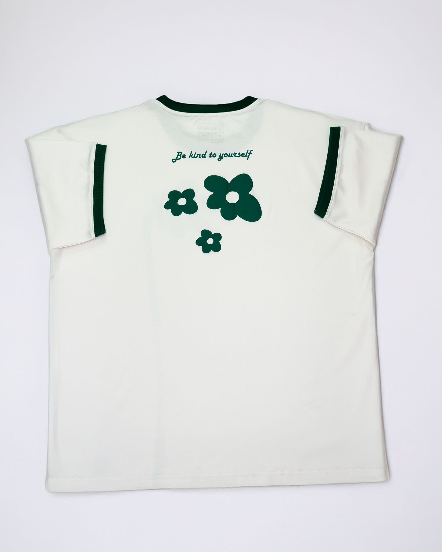 Cream oversized flower t-shirt featuring green flower graphics and a kindness message on the back