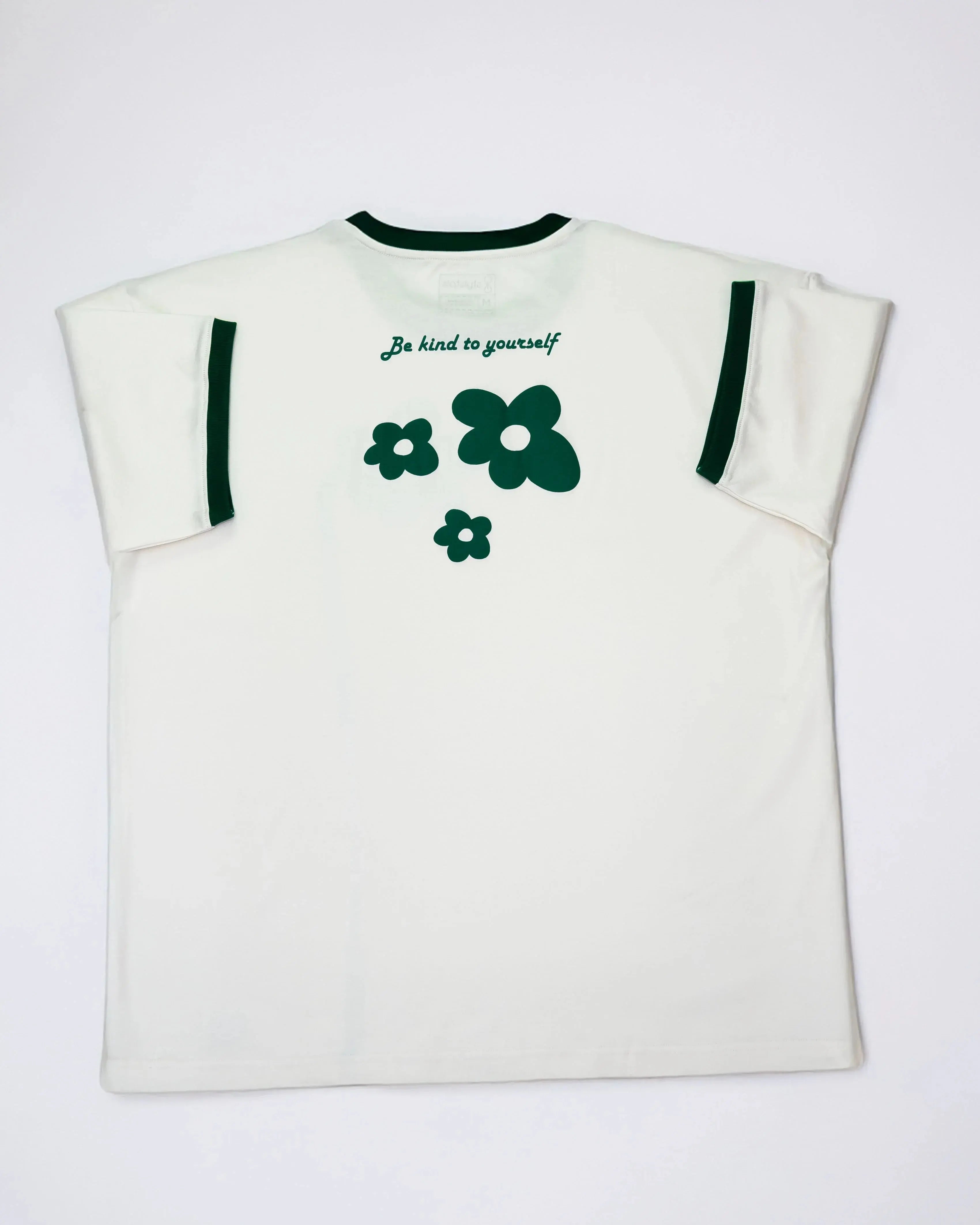 Cream oversized flower t-shirt featuring green flower graphics and a kindness message on the back