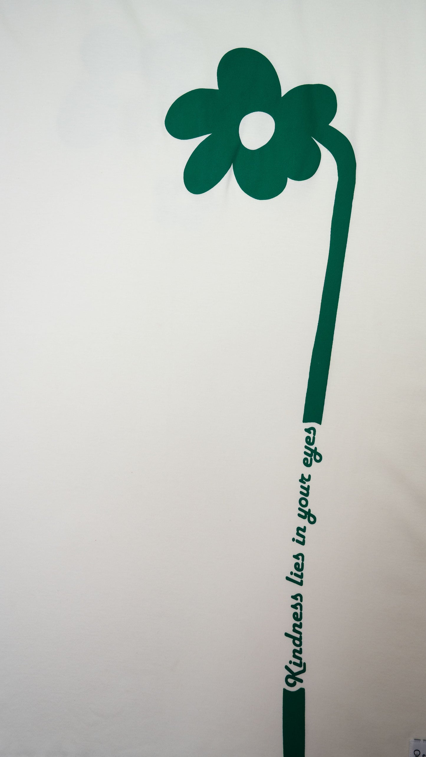 Cream oversized flower t-shirt featuring a large green flower design and the text kindness lies in your eyes