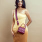 Stylish model wearing a crimson mini sling bag paired with a yellow dress for a chic look