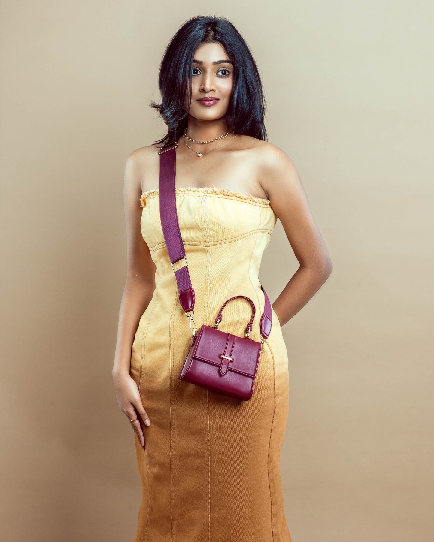 Stylish model wearing a crimson mini sling bag paired with a yellow dress for a chic look