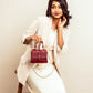 Stylish woman holding a crimson mini sling bag with a gold chain strap and elegant design