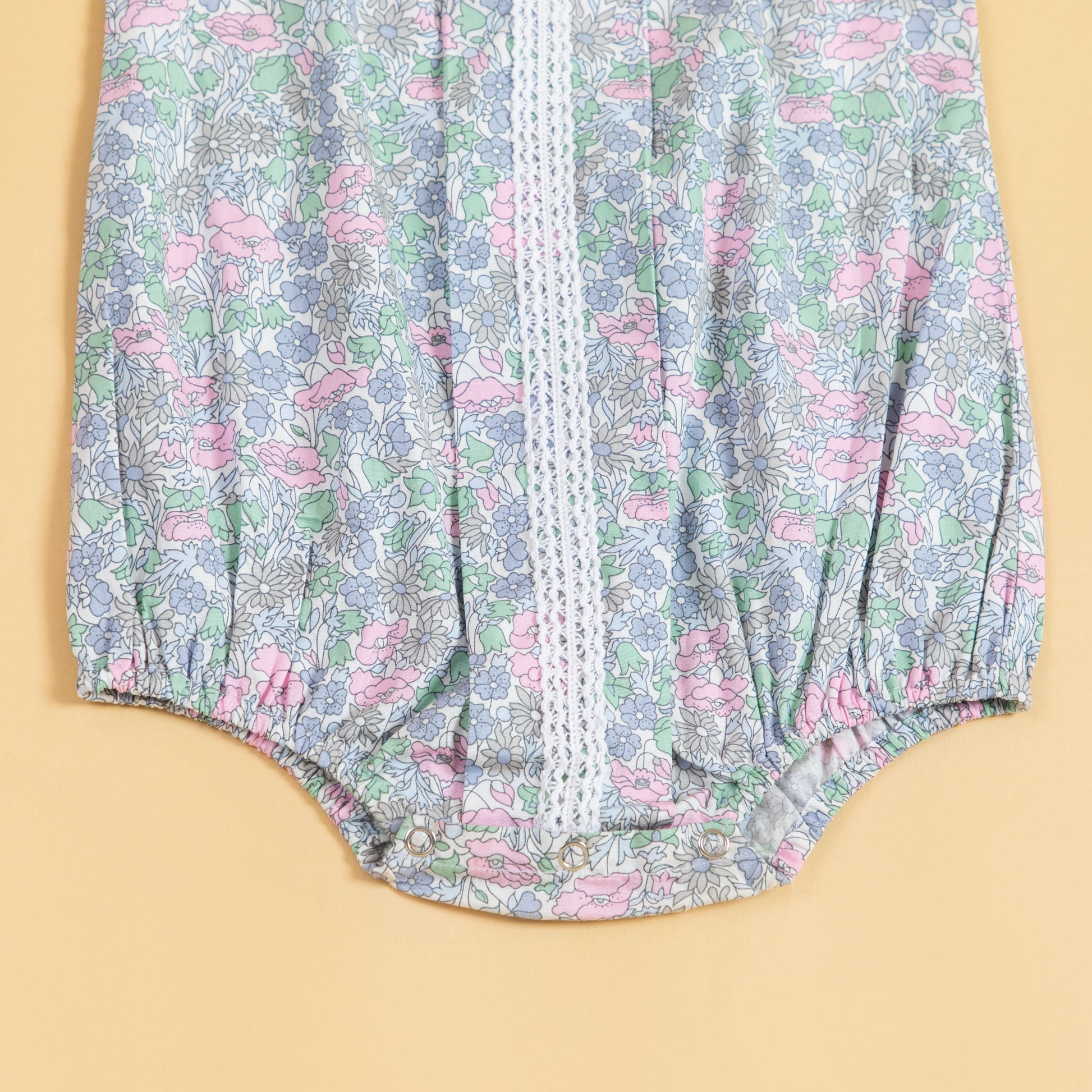 Cute summer romper for babies with floral print and lace details in pastel colors