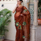Elegant model wearing a designer brown saree for wedding with floral embroidery against a heritage backdrop