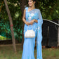 Elegant designer chiffon saree with floral painting in blue, styled with a white handbag and accessories
