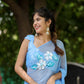 Model wearing a designer chiffon saree with floral painting in a serene outdoor setting