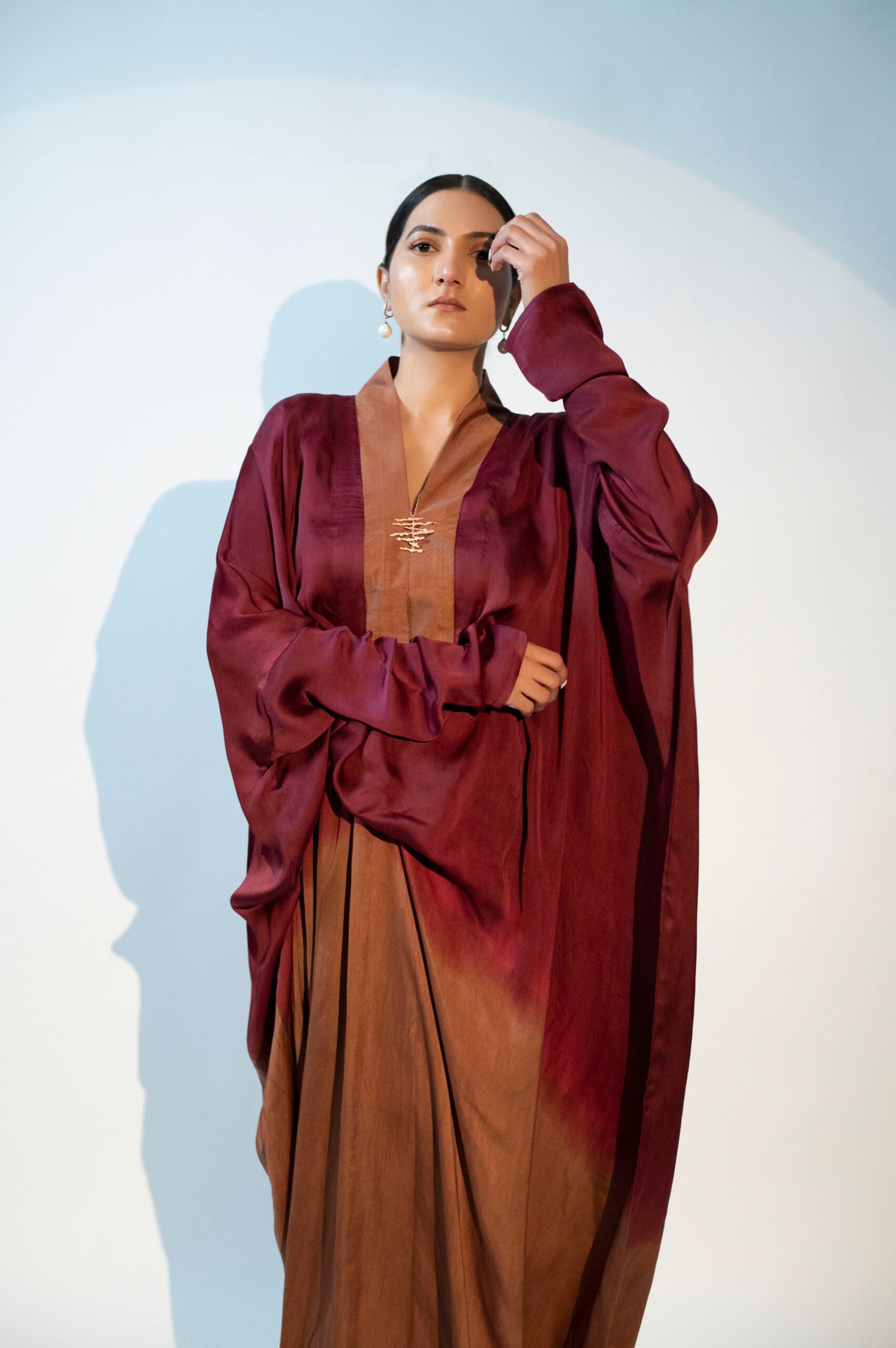 Elegant designer evening gown for women featuring flowing sleeves and rich burgundy tones