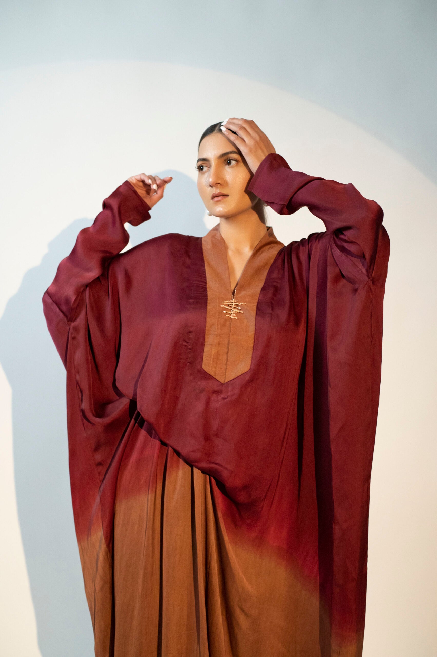 Elegant designer evening gown for women in rich burgundy and brown hues with dramatic sleeves