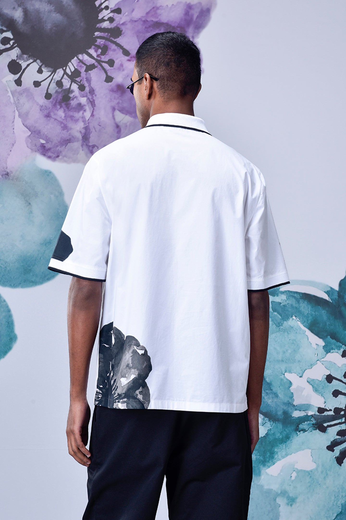 Back view of mens floral polo shirt by Stylera featuring white fabric with black floral accents
