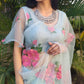 Designer party wear organza saree in light blue with floral prints, styled elegantly for festive occasions
