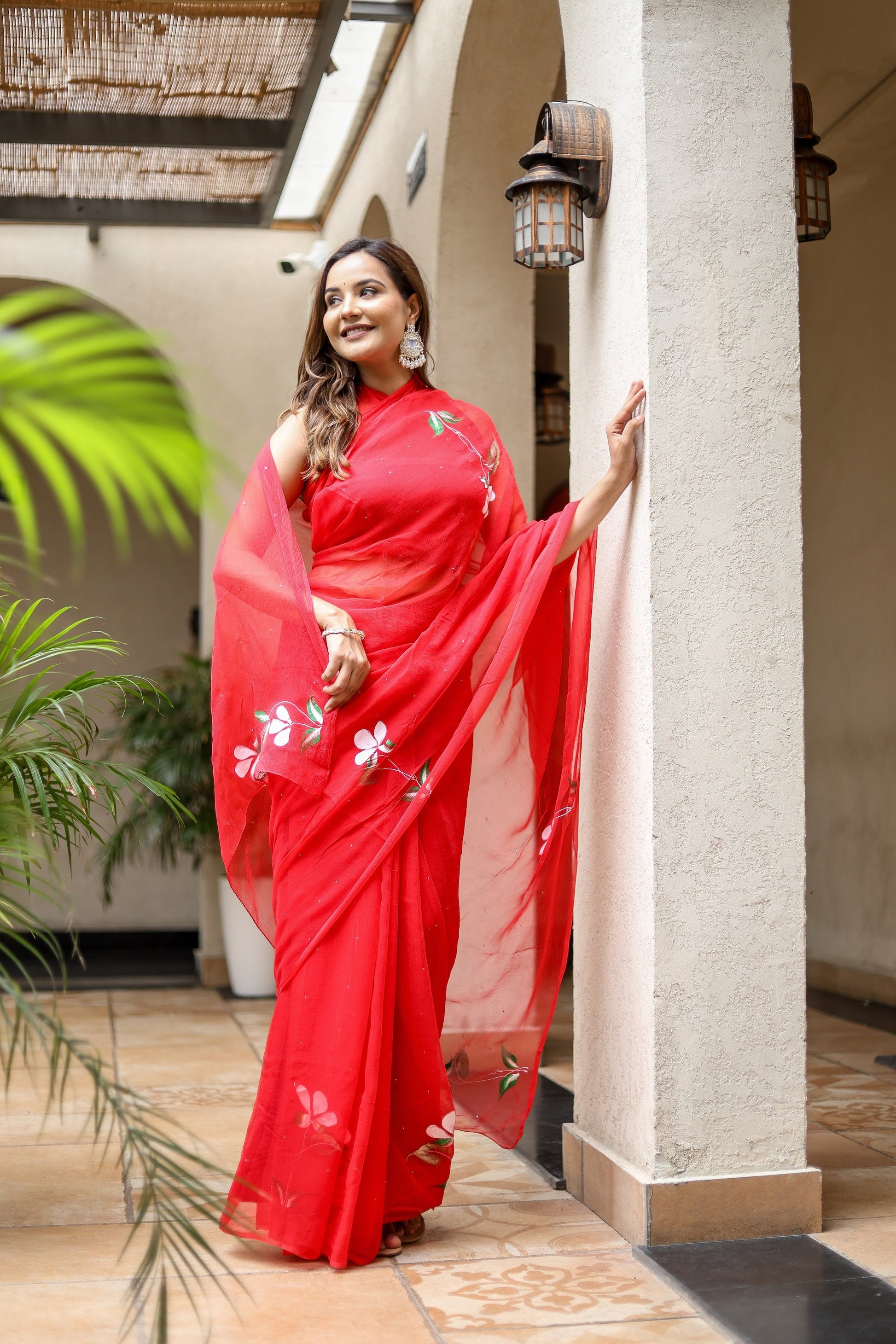 Elegant designer red saree for weddings featuring floral embroidery and a flowing silhouette