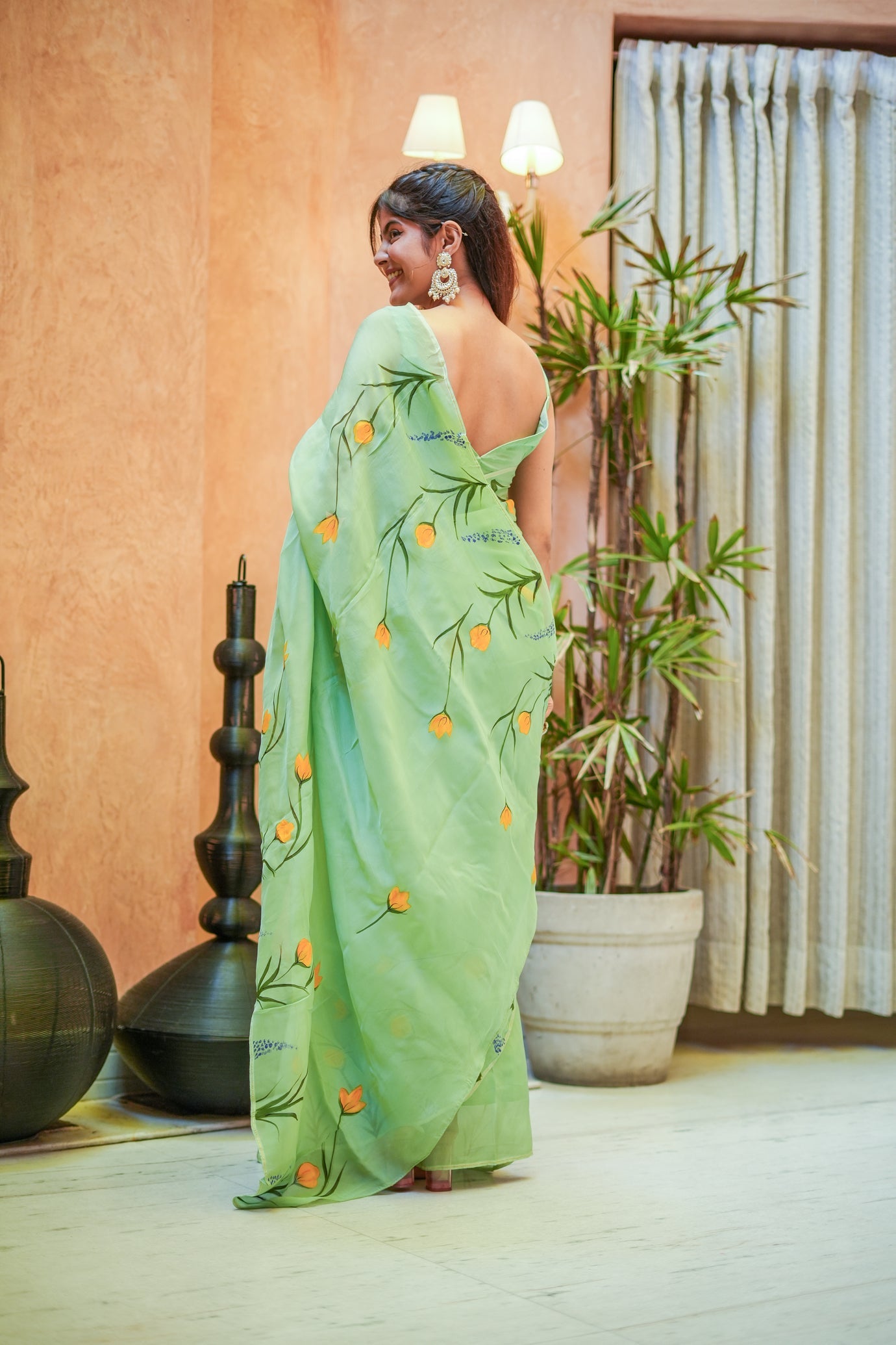 Elegant green designer saree for women featuring floral designs, styled with statement earrings