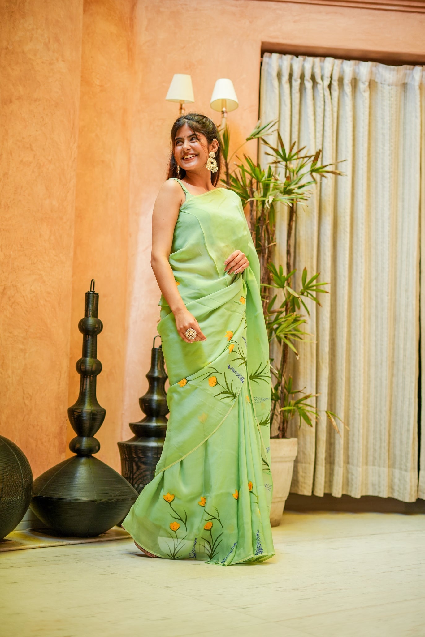 Model wearing a light green designer saree for women with floral patterns, showcasing elegance and style