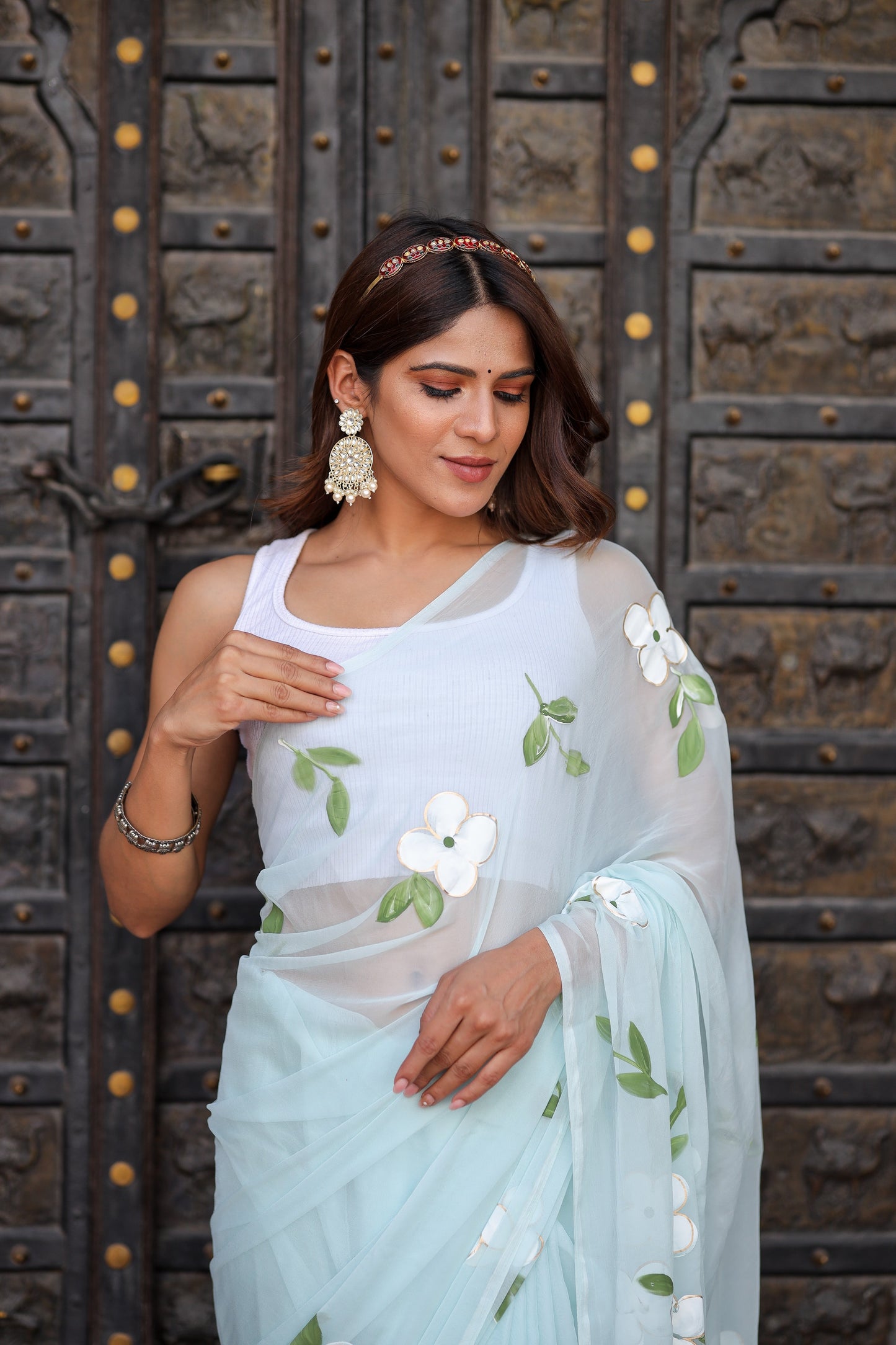 Model wearing a light blue designer saree with floral embroidery and delicate leaves detail