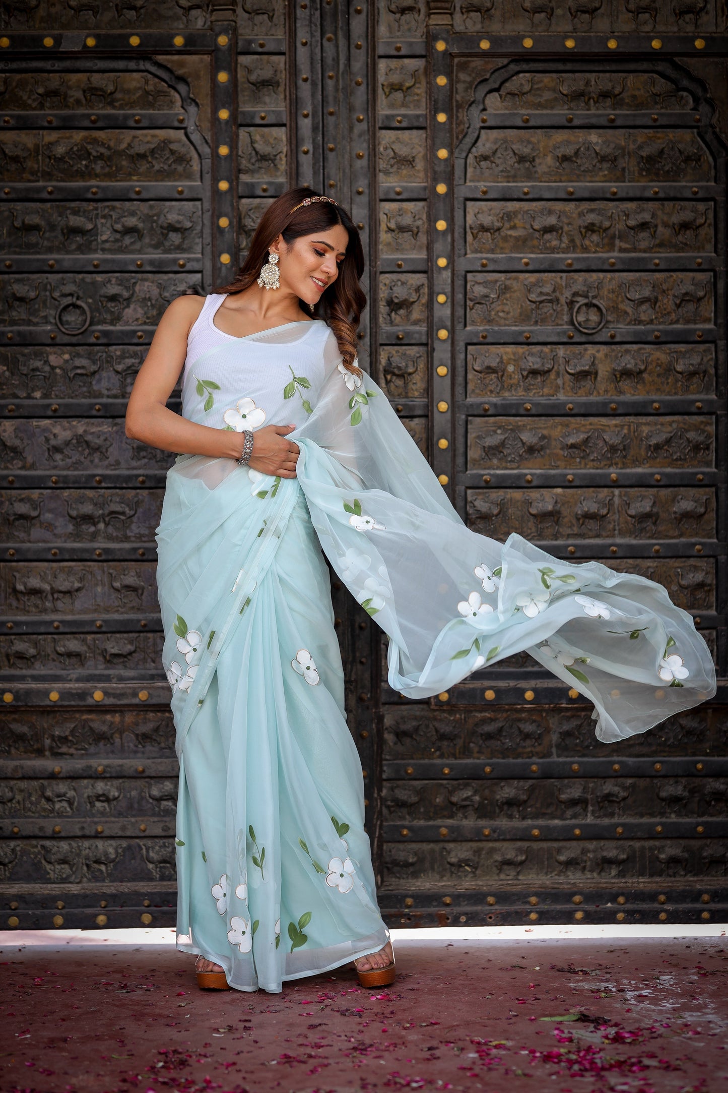 Elegant light blue designer saree with floral embroidery, styled with matching accessories